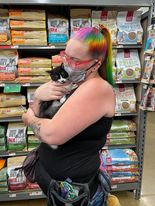 A woman with rainbow hair holds a kitten before it's cat claw clipping appointment.